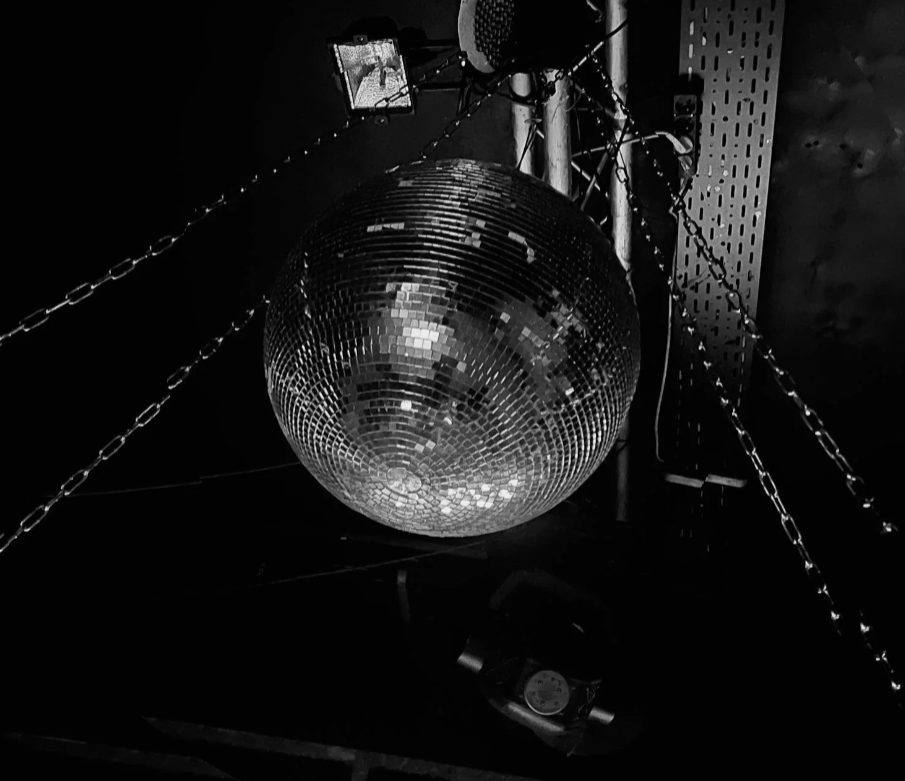 Zwart-witfoto van een discobal tussen kettingen en stagingmateriaal